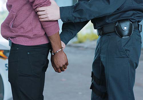 Close-up of a policeman handcuffing a young man suspected of a crime.
