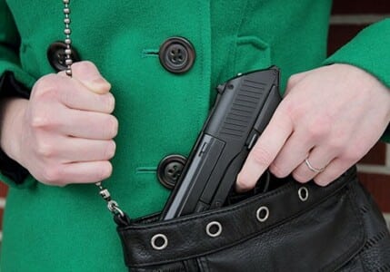 A woman taking a handgun out of her purse.