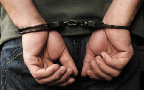 A man in handcuffs with his hands behind his back.