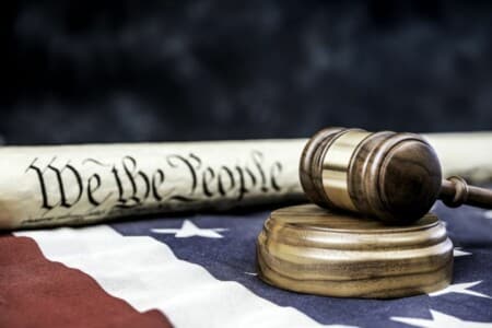 A gavel and a copy of the US constitution on top of an American flag.