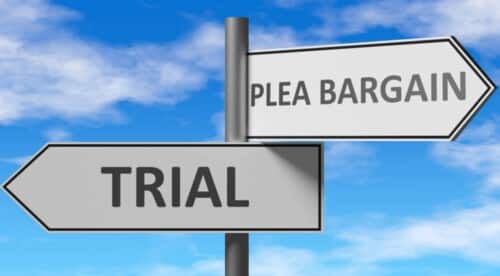 2 signs saying "TRIAL" pointing to the left, and "PLEA BARGAIN" pointing to the right.