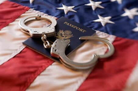 Handcuffs on top of a US passport and US flag.