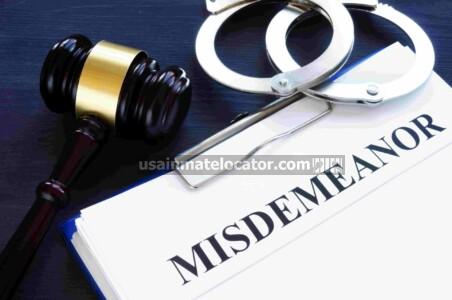 Handcuffs and a gavel on top of papers titled "Misdemeanor".