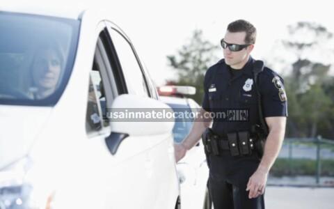 A police officer touching the tail light of a car during a traffic stop.