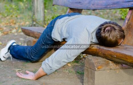 Public drunkenness: A drunk man asleep on a park bench.