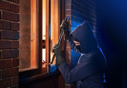 A man using a crowbar to break into a house.