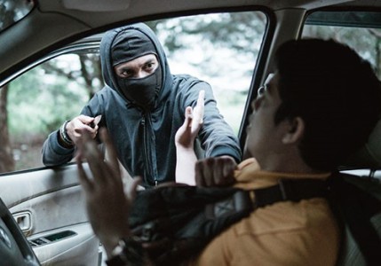 A masked man with a knife threatening another man who is sitting in his car.