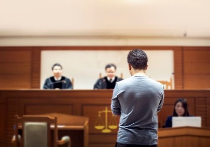 A man standing in court listening to the judge.