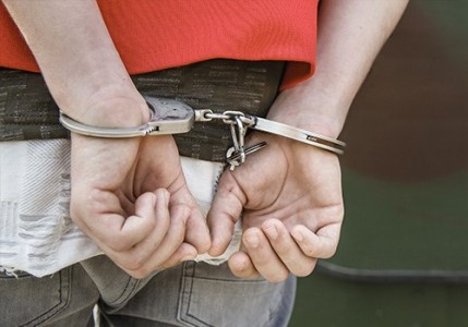 A closeup of a man's hands handcuffed behind his back.