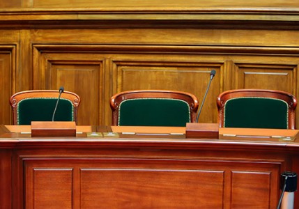 An empty vintage courtroom table and chairs with microphones.