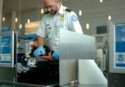 TSA agent searching through a suitcase.
