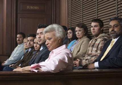 Jurors of multiple ethnicities on the jury stand in a courtroom.