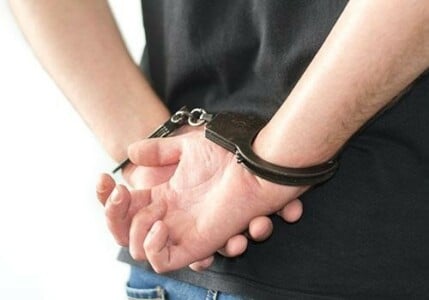 Closeup of a man's hands handcuffed behind his back.