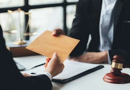 An attorney handing an envelope containing a plea deal over to another attorney.