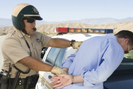 A highway patrol officer placing someone under arrest.