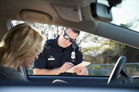 A police officer writing a ticket at a traffic stop.